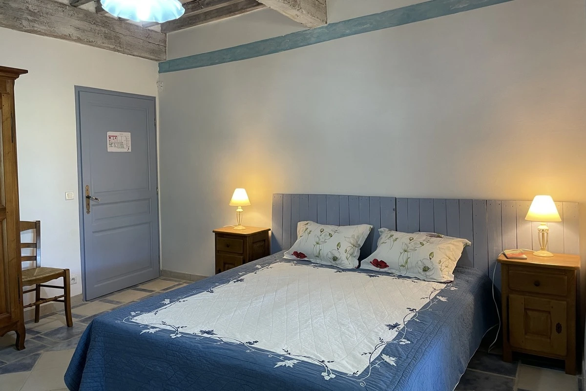 Chambre d'hôtes avec lit double au Château de la Gabelle en Drôme provençale, décorée dans des tons bleus avec un style cosy et rustique.