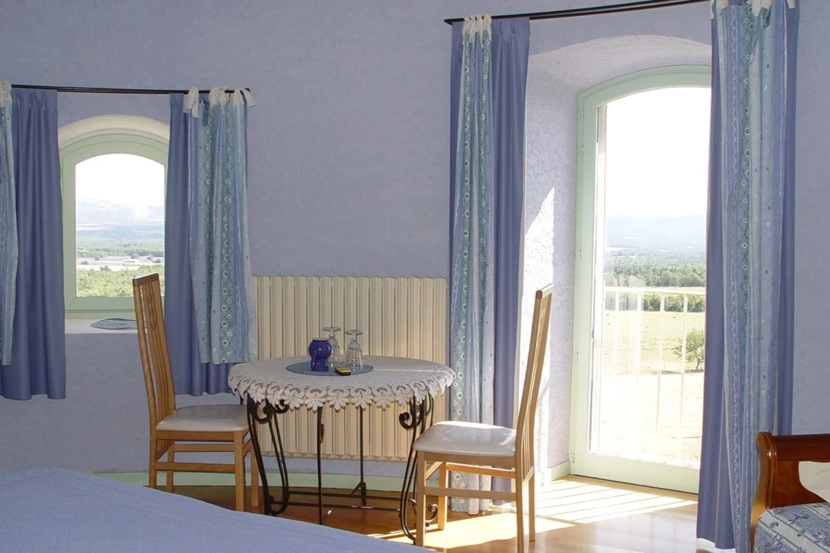 Chambre d'hôtes au Château de la Gabelle en Drôme provençale, avec vue panoramique sur la vallée et coin repas près de la fenêtre.