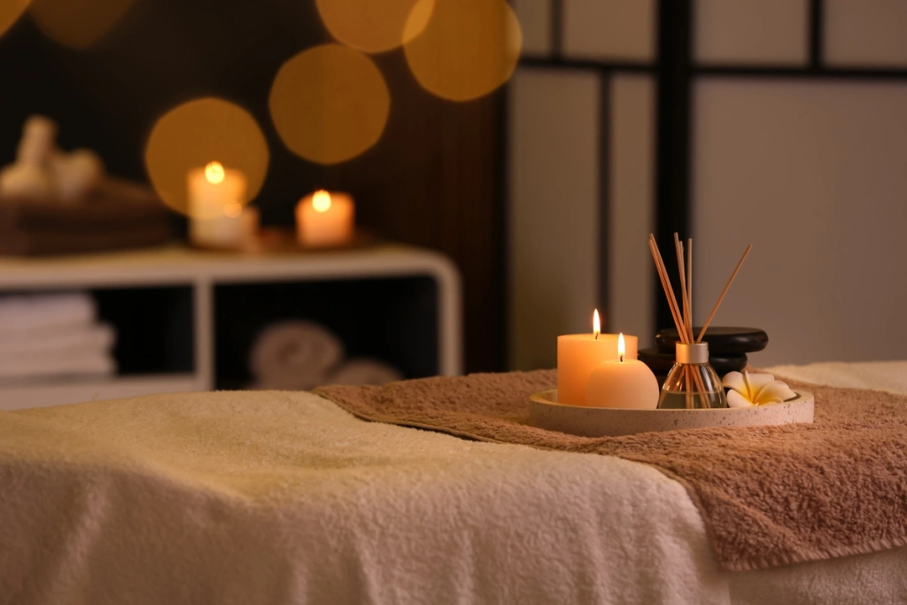 Table de massage avec des bougies allumées et des huiles essentielles, créant une ambiance relaxante au Château de la Gabelle en Drôme provençale.